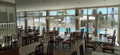 a restaurant with tables and chairs in a room with windows at Hotel Yasemin in Erdek