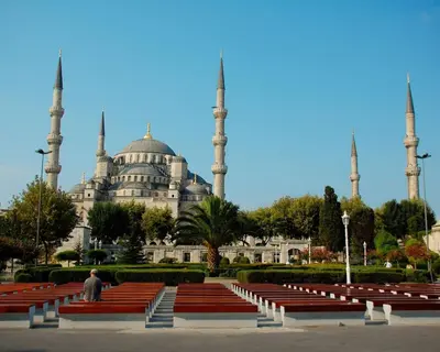 a man sitting in front of a building with two mosques at Ersari Hotel in Istanbul
