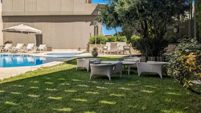 a group of chairs and tables in the grass next to a pool at Istanbul Gonen Hotel in Istanbul