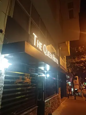 a sign on the exterior of a hotel at night at The Queen Hotel in Istanbul