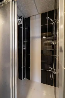 a bathroom with a shower with black tiles at Pi Home & Apartments in Istanbul