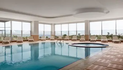 a pool in a hotel with chairs and windows at Ramada by Wyndham Tekirdağ in Tekirdag
