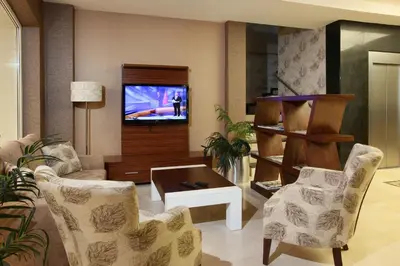 a living room with a tv and chairs and a table at Balturk House Hotel in Kocaeli