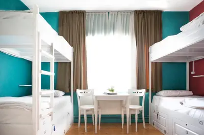 a bedroom with two bunk beds and a table and chairs at Cheers Midtown Hostel in Istanbul