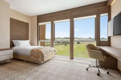 a bedroom with a bed and a desk and windows at Wyndham Cerkezkoy in Cerkezkoy