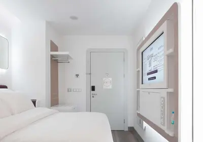 a white bedroom with a bed and a flat screen tv at YOTELAIR Istanbul Airport, Duty free - International Transit area in Istanbul