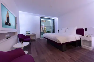 a hotel room with a large bed and purple chairs at YOTELAIR Istanbul Airport, Duty free - International Transit area in Istanbul