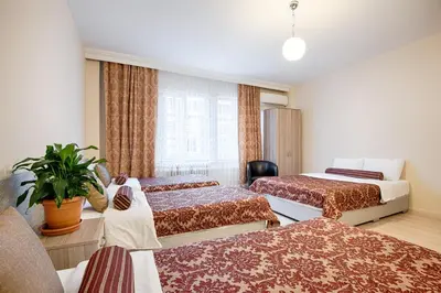 a hotel room with three beds and a plant at DİNAR HOTEL in Istanbul