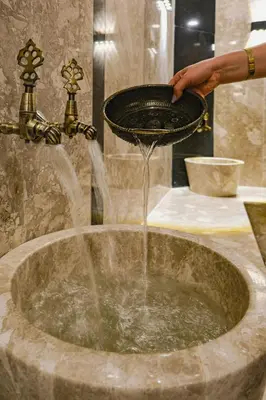 a person pouring water into a bowl in a sink at Vital Thermal Hotel & SPA in Termal