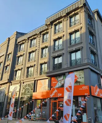 a tall building with an orange sign in front of it at Kızılkaya Business Otel in Korfez