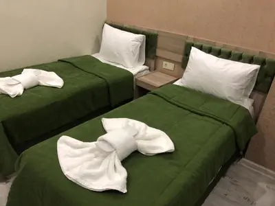 two beds with green sheets and white towels on them at Kaya Madrid Hotel in Istanbul