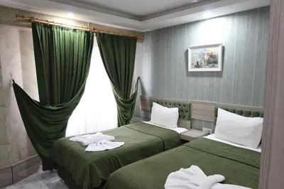 two beds in a hotel room with green curtains at Kaya Madrid Hotel in Istanbul