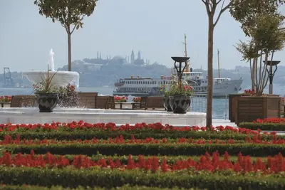 a garden with flowers and a cruise ship in the water at Four Seasons Hotel Istanbul at the Bosphorus in Istanbul