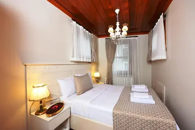 a bedroom with a bed with white sheets and a chandelier at Elyka Hotel in Istanbul