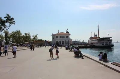 a group of people walking on a sidewalk next to the water at Kadikoy Otel in Istanbul