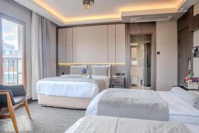 a hotel room with two beds and a chair at BEST GARDEN HOTEL in Istanbul