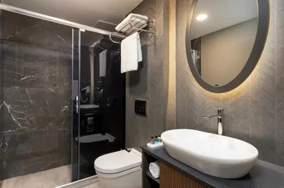 a bathroom with a sink and a toilet and a mirror at Miracle Istanbul Asia Airport Hotel & Spa in Istanbul