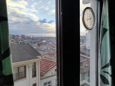 a clock on a window with a view of a city at ivy hostel cafe in Istanbul