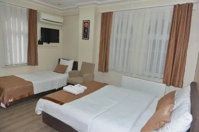 a hotel room with two beds and a chair at Teras Hotel Kağıthane in Istanbul