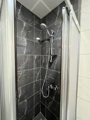 a black tiled shower with a shower head at Chambers of the Boheme in Istanbul