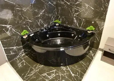 a black marble bathroom with a black tub with two plants at Sahil Hotel Pendik in Tuzla