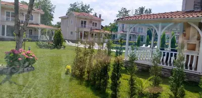 a house with a porch and a yard with flowers at PALACE KIRKPINAR in Sakarya