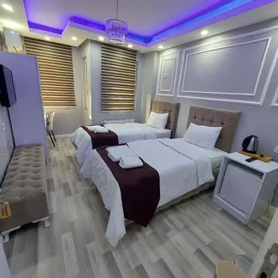 two beds in a hotel room with purple lighting at Modena Hotel in Istanbul