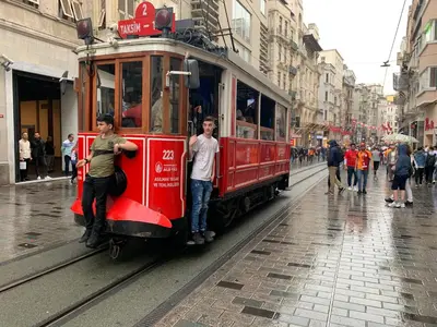 a red trolley car on a street with people at taksim diamond hotel in Istanbul