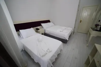 two beds in a hotel room with white sheets at taksim diamond hotel in Istanbul