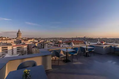 a rooftop bar with tables and chairs and a view of the city at Galata Times Hotel in Istanbul
