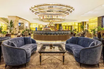 a lobby with two blue chairs and a chandelier at CVK Park Bosphorus Hotel Istanbul in Istanbul