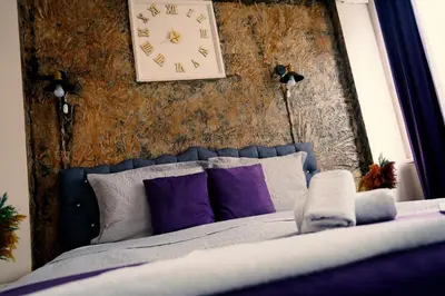 a clock on a wall above a bed with purple pillows at Medellin Apart Hotel Istanbul in Istanbul