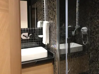 a black tiled bathroom with a shower and a sink at Four-G Hotel in Istanbul