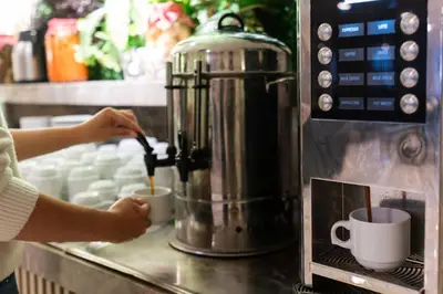 a woman is making cups of coffee in a microwave at Four Sides Taksim Lion Hotel&Spa in Istanbul