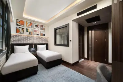 a bedroom with two beds and a chair in it at DeCamondo Galata, a Tribute Portfolio Hotel in Istanbul