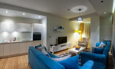 a living room with blue couches and a kitchen at Armoni Residence & Hotel in Istanbul