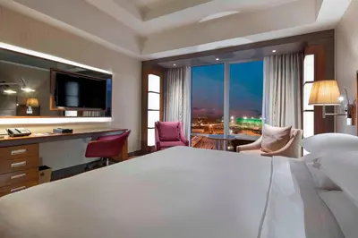 a hotel room with a large white bed and a desk at Sheraton Bursa Hotel in Bursa