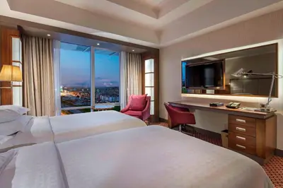 a hotel room with two beds and a desk and a window at Sheraton Bursa Hotel in Bursa