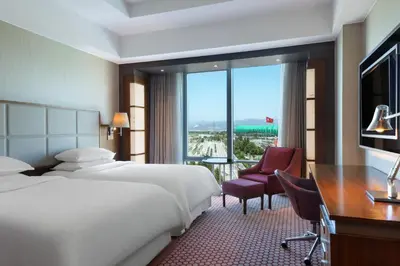 a hotel room with two beds and a desk and a window at Sheraton Bursa Hotel in Bursa