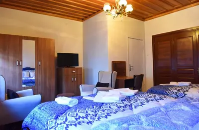 a bedroom with two beds with chairs and a tv at ÖZ Butik Otel Antik Kent Myrleia in Mudanya