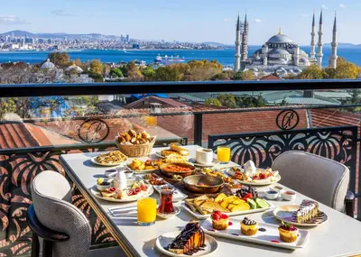 a breakfast table with food on a balcony with a view of the mosque at Rast Hotel Sultanahmet in Istanbul