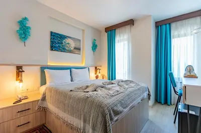 a bedroom with a bed and a desk and windows at Stanpoli Hostel in Istanbul