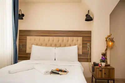 a bedroom with a white bed with a wooden headboard at Corner Garden Hotel in Istanbul