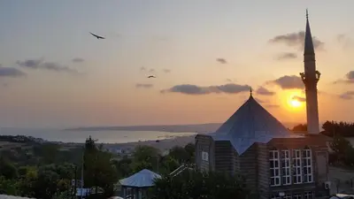 a mosque with a minaret in front of a sunset at Doğa Villa Guest House in Buyukcekmece