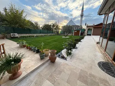 a patio with potted plants and a mosque in the background at Doğa Villa Guest House in Buyukcekmece