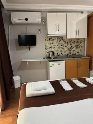a room with a bed and a kitchen with white cabinets at Tavra hotel in Istanbul