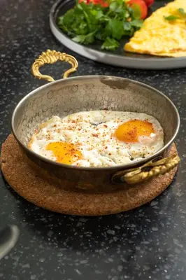 two fried eggs in a pan on a table at Elm Suite Hotel in Istanbul