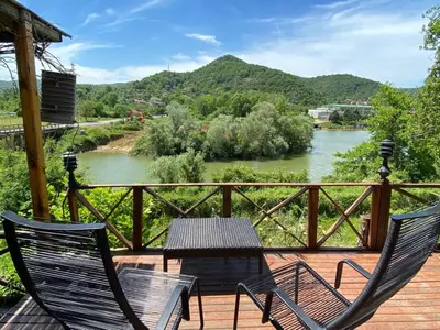 two chairs and a table on a deck overlooking a river at Ağva Green River Hotel in Agva