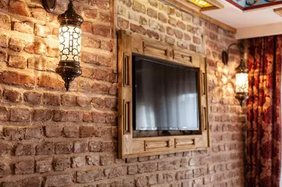 a television mounted on a brick wall with a lamp at Enderun by Otantik Suites in Istanbul