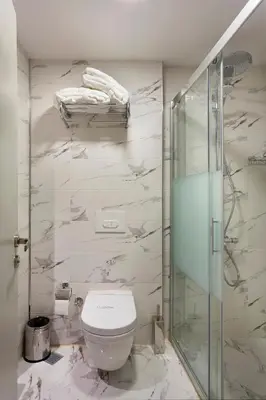 a bathroom with a toilet and a glass shower at Güner Business Hotel in Istanbul
